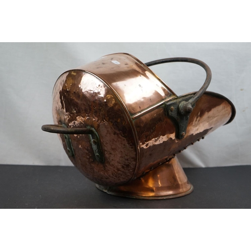 570 - A large copper coal scuttle with old riveted repair.