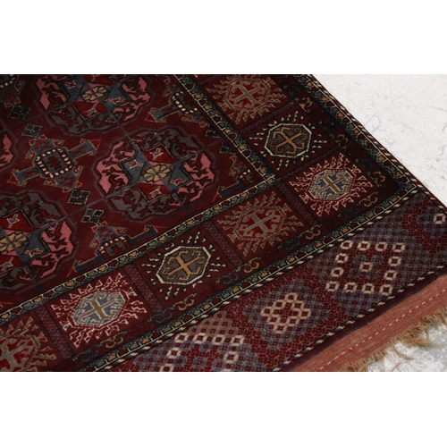 834 - Dark Red Ground Wool Rug with Geometric Pattern to centre surrounded by a border of square panels, 1... 