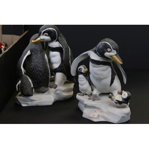 682 - A large collection of ceramic and resin penguin ornaments contained within two boxes.