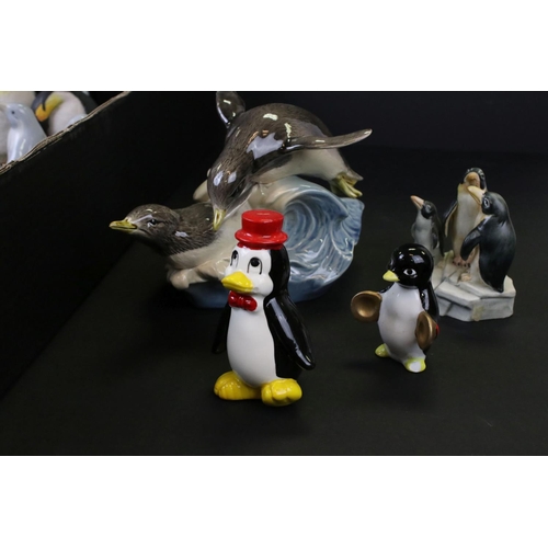 682 - A large collection of ceramic and resin penguin ornaments contained within two boxes.