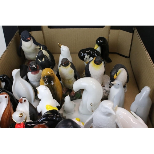 682 - A large collection of ceramic and resin penguin ornaments contained within two boxes.