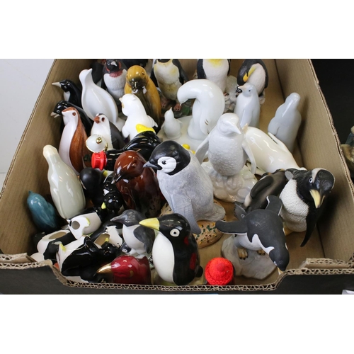 682 - A large collection of ceramic and resin penguin ornaments contained within two boxes.