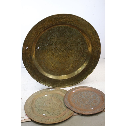 687 - A very large brass charger with stylized floral decoration 91 cm diameter together with two others s... 