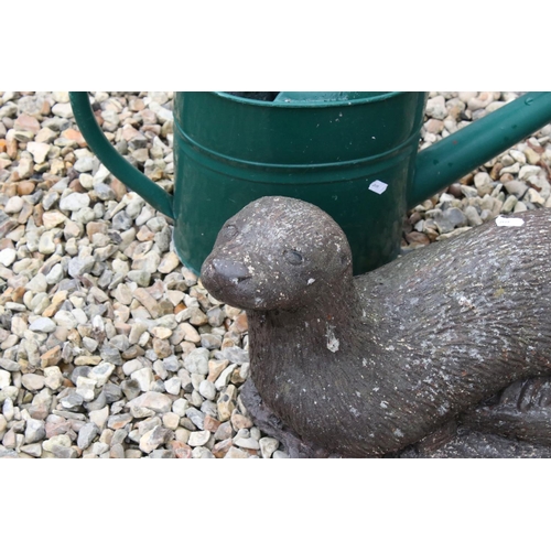 698 - A green metal watering can together with a stone Otter garden ornament.