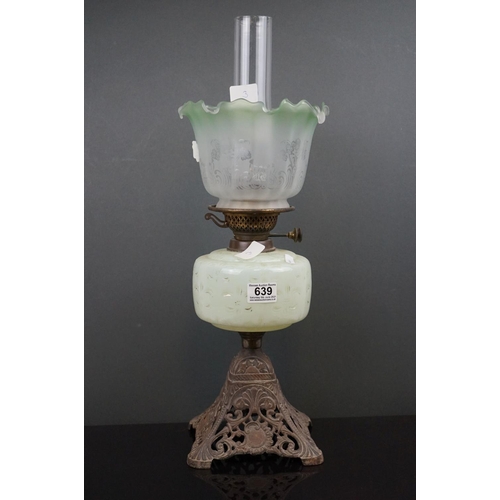 639 - An antique early 20th century oil lamp with pierced metal base, light green well & shade with floral... 