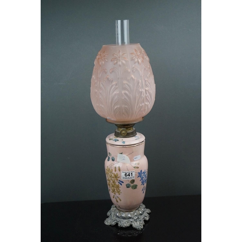 641 - A pink ground ceramic oil lamp decorated with butterflies and fauna, mounted on a metal base, of roc... 