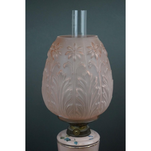 641 - A pink ground ceramic oil lamp decorated with butterflies and fauna, mounted on a metal base, of roc... 