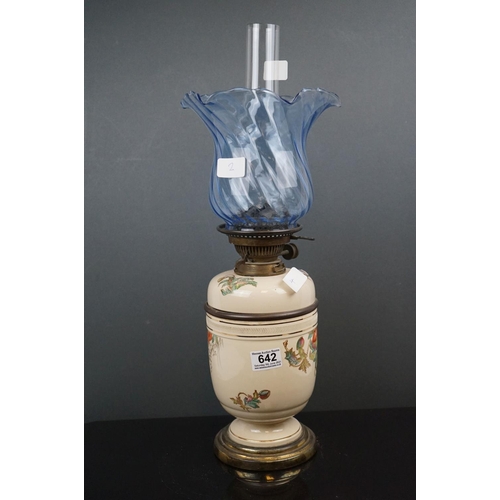 642 - A 20th century porcelain oil lamp with floral decoration and blue twisted scallop topped shade.