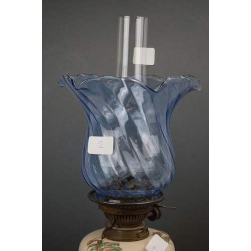 642 - A 20th century porcelain oil lamp with floral decoration and blue twisted scallop topped shade.