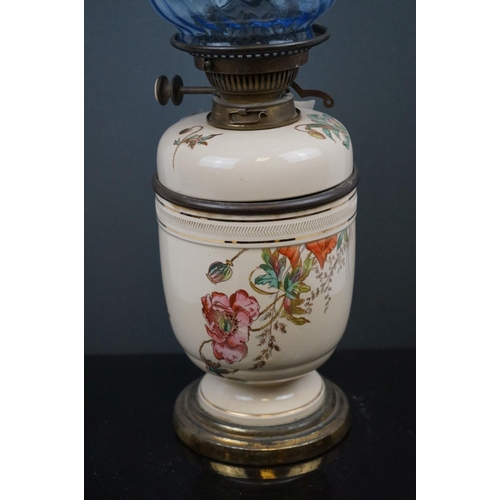 642 - A 20th century porcelain oil lamp with floral decoration and blue twisted scallop topped shade.