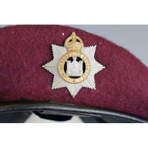 316 - A British Military Red Beret Cap Complete With King Crown Cap Badge To The Devonshire Regiment.