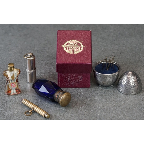 214 - A small group of collectables to include a blue glass scent bottle, watch winder and a pin cushion.