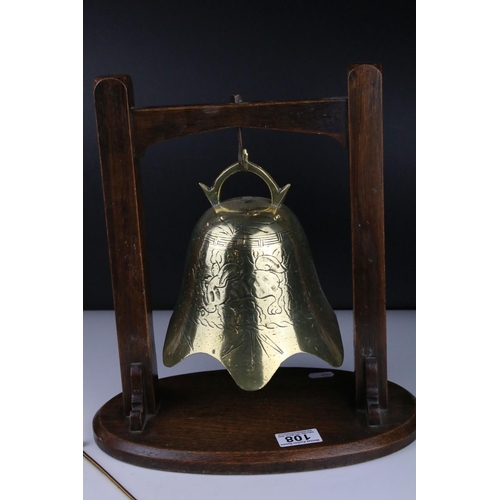 108 - Brass engraved Temple Bell with striker held on a Hardwood Stand, 34cm high