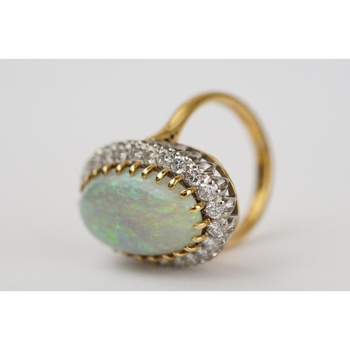 20 - Opal and diamond 18ct yellow gold and white gold set cluster ring, the large oval cabochon cut preci... 