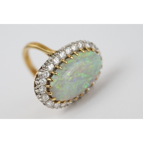 20 - Opal and diamond 18ct yellow gold and white gold set cluster ring, the large oval cabochon cut preci... 