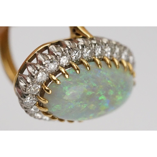 20 - Opal and diamond 18ct yellow gold and white gold set cluster ring, the large oval cabochon cut preci... 