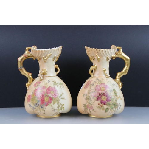 13 - Pair of Royal Worcester Blush Ivory Jugs, decorated with flowers and with gilt moulded handles in th... 