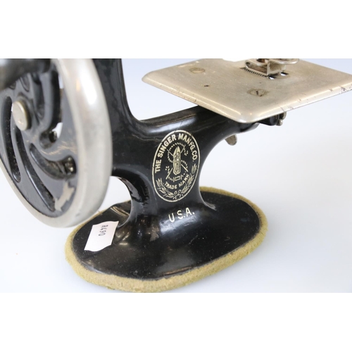 145 - An antique cast iron miniature Singer sewing machine together with a miniature A.R.C. Chesterton iro... 