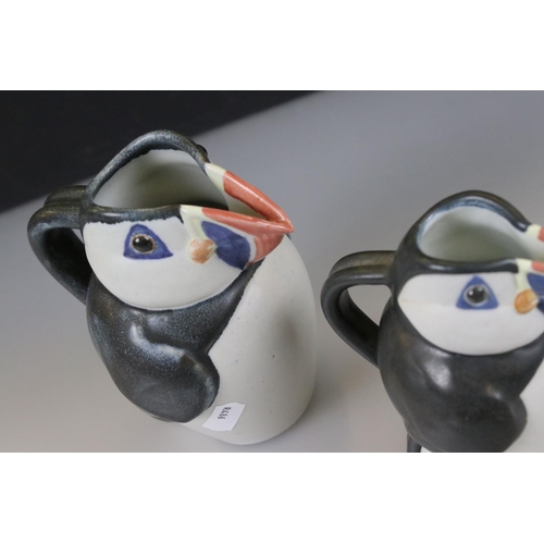 27 - John O'Groats Pottery - Set of Three Graduating Puffin Jugs, largest 20cm high together with another... 