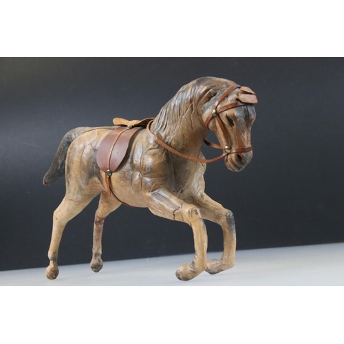 83 - Four leather horse models, with saddles and harnesses, tallest 32cm