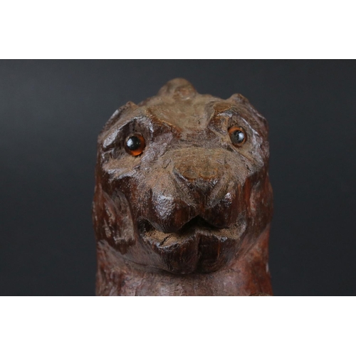 98 - Black Forest style naive carved Lion sitting on his haunches with glass eyes, 33cm high