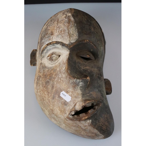 358 - A collection of four wooden carved tribal mask together with associated book.