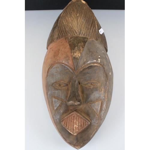 358 - A collection of four wooden carved tribal mask together with associated book.