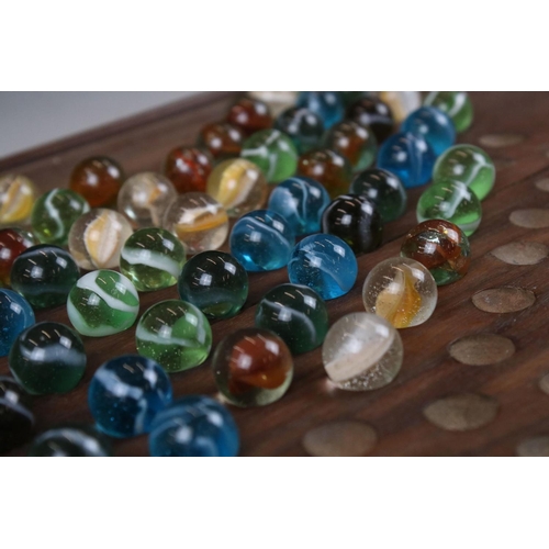 271 - An early to mid 20th century wooden solitaire board together with marbles.