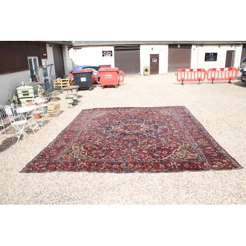 633 - Large Wool Red Ground Rug decorated with geometric floral pattern within a border, 483cm x 417cm