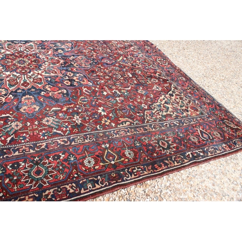 633 - Large Wool Red Ground Rug decorated with geometric floral pattern within a border, 483cm x 417cm