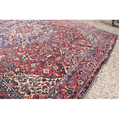 633 - Large Wool Red Ground Rug decorated with geometric floral pattern within a border, 483cm x 417cm