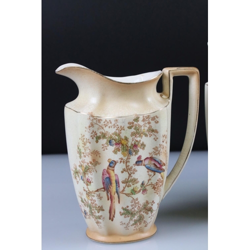 48 - Set of Three Crown Ducal Graduating Blush Ivory Jugs decorated with exotic birds, largest 22cm