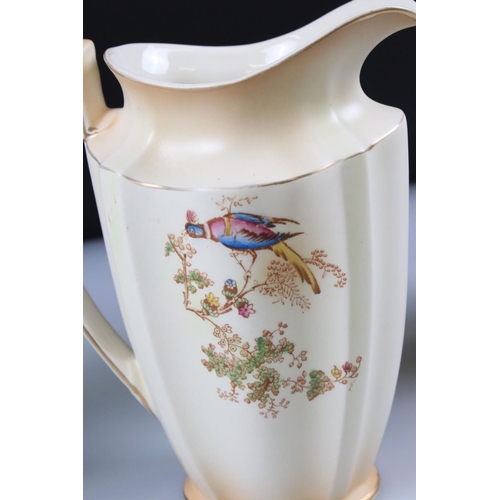 48 - Set of Three Crown Ducal Graduating Blush Ivory Jugs decorated with exotic birds, largest 22cm