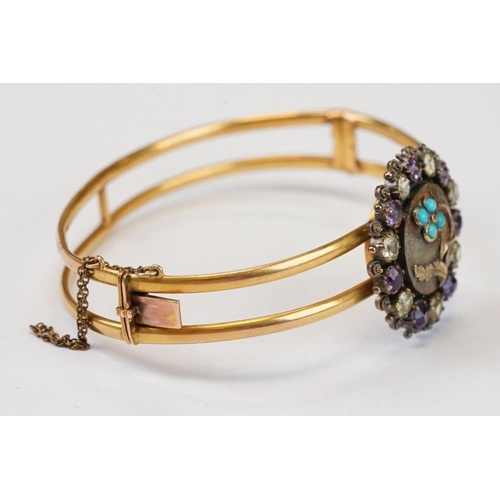 104 - Late Victorian / Edwardian amethyst, citrine and turquoise yellow metal hinged bangle; the central m... 