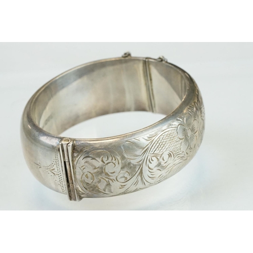 303 - Silver hinged bracelet, engraved floral and foliate decoration to the upper half, tongue and box cla... 