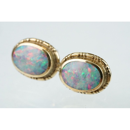 134 - Pair of opal doublet 9ct yellow gold stud earrings, the oval opal displaying indigo, blue, green and... 