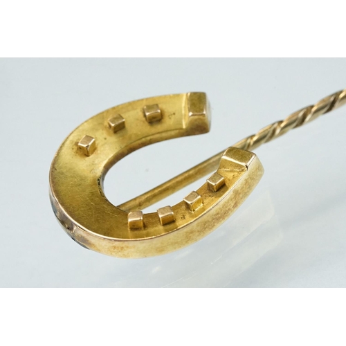 140 - 19th century yellow metal stick pin modelled as a horseshoe; length of head approx 2cm