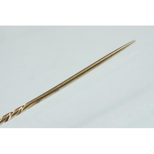 140 - 19th century yellow metal stick pin modelled as a horseshoe; length of head approx 2cm