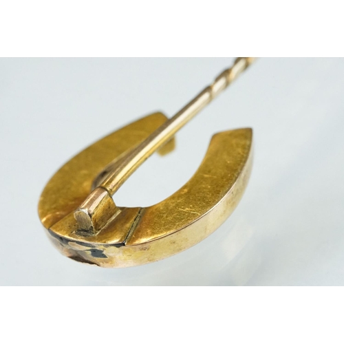 140 - 19th century yellow metal stick pin modelled as a horseshoe; length of head approx 2cm