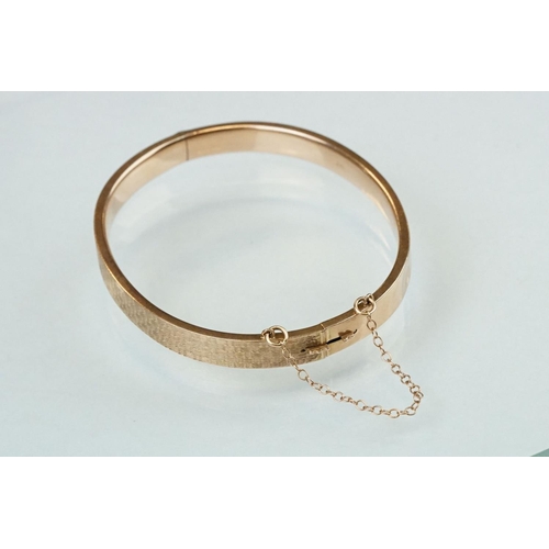 232 - 9ct rose gold hinged bangle, engraved textured design to upper half, the tongue and box clasp with s... 