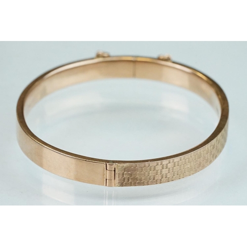 232 - 9ct rose gold hinged bangle, engraved textured design to upper half, the tongue and box clasp with s... 