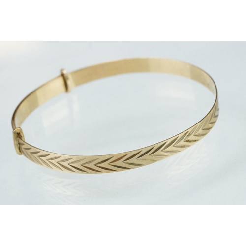 233 - 9ct yellow gold Christening bangle, engraved stylised foliate decoration, width approx 5mm