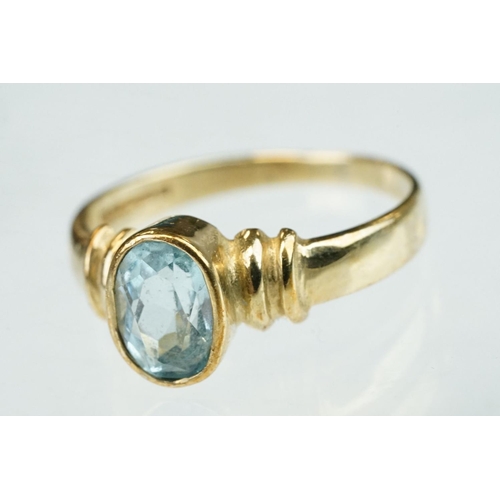 256 - Topaz solitaire 9ct yellow gold dress ring, the oval mixed cut blue topaz measuring approx 7mm x 4.5... 