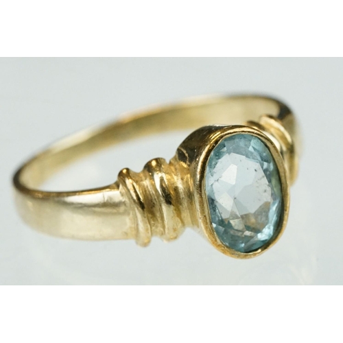 256 - Topaz solitaire 9ct yellow gold dress ring, the oval mixed cut blue topaz measuring approx 7mm x 4.5... 