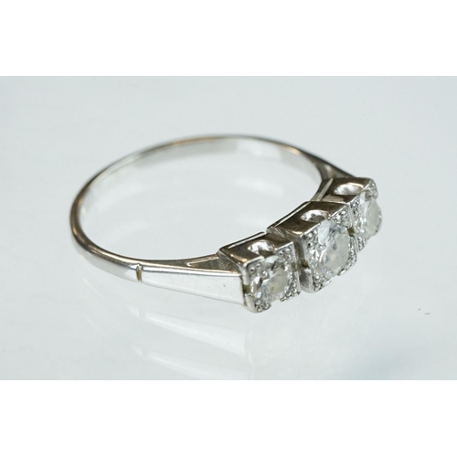 164 - Diamond three stone unmarked white gold ring, three graduated round brilliant cut diamonds, within s... 