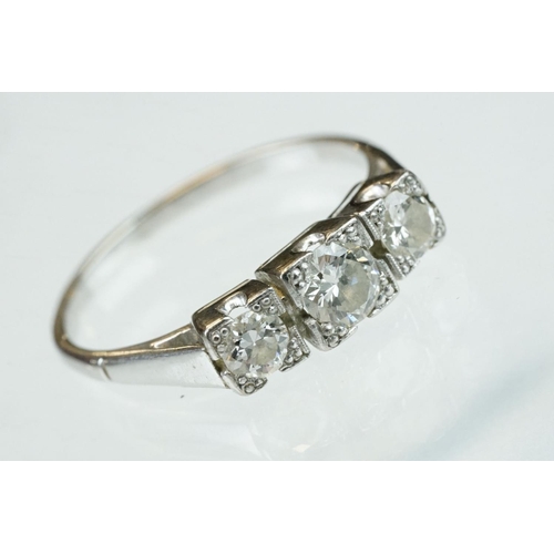 164 - Diamond three stone unmarked white gold ring, three graduated round brilliant cut diamonds, within s... 