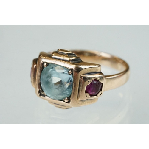 291 - Topaz and ruby rose metal ring, the round mixed cut blue topaz diameter approx 7mm, claw and flush s... 