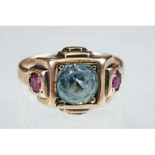 291 - Topaz and ruby rose metal ring, the round mixed cut blue topaz diameter approx 7mm, claw and flush s... 