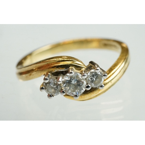 300 - Diamond 18ct yellow gold three stone crossover ring, round brilliant cut graduated diamonds, the cen... 