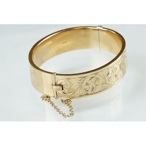 36 - 9ct yellow gold hinged bangle, engraved foliate scroll decoration to the upper half, tongue and box ... 